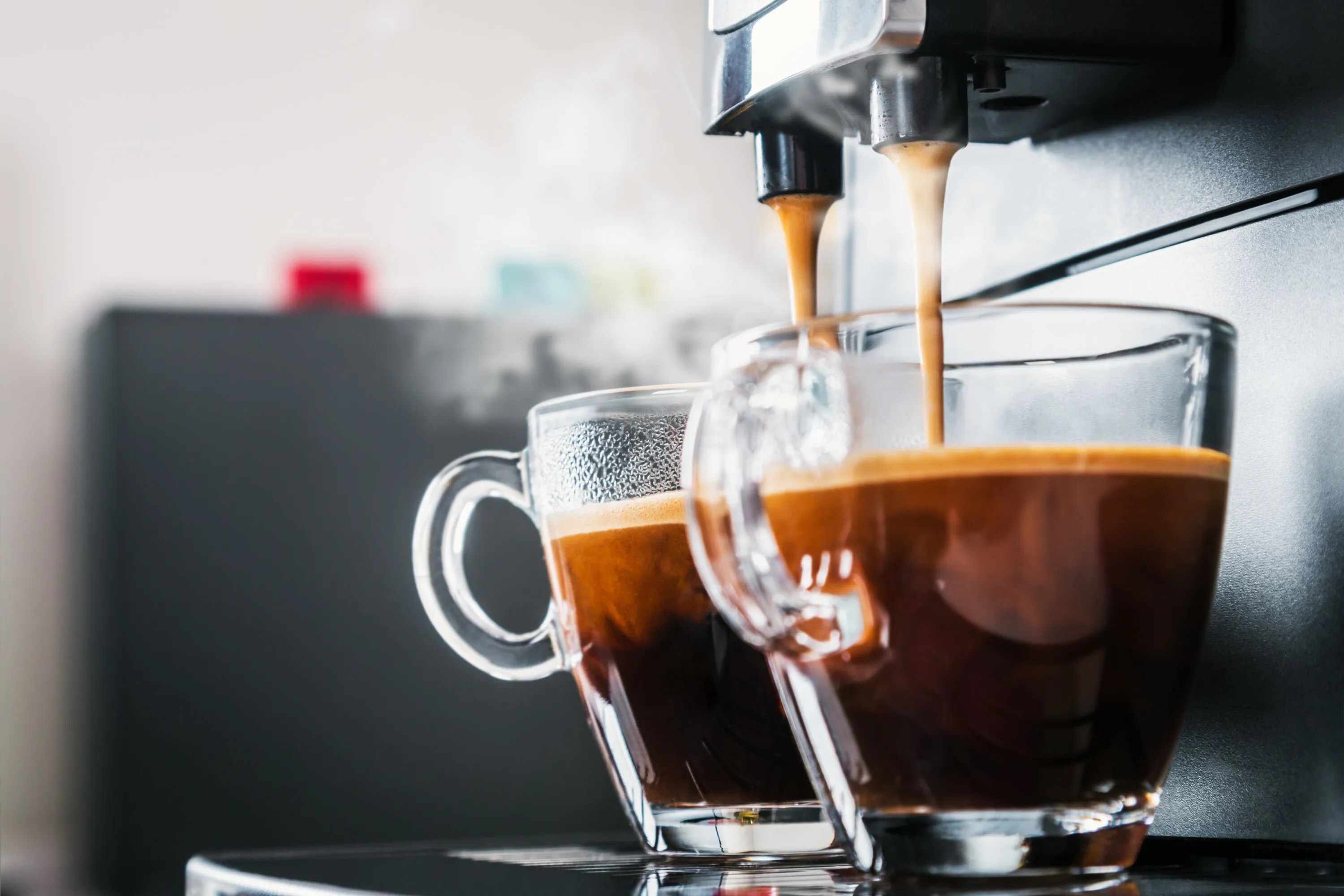 Espresso läuft aus einem Kaffeevollautomaten in zwei Gläser