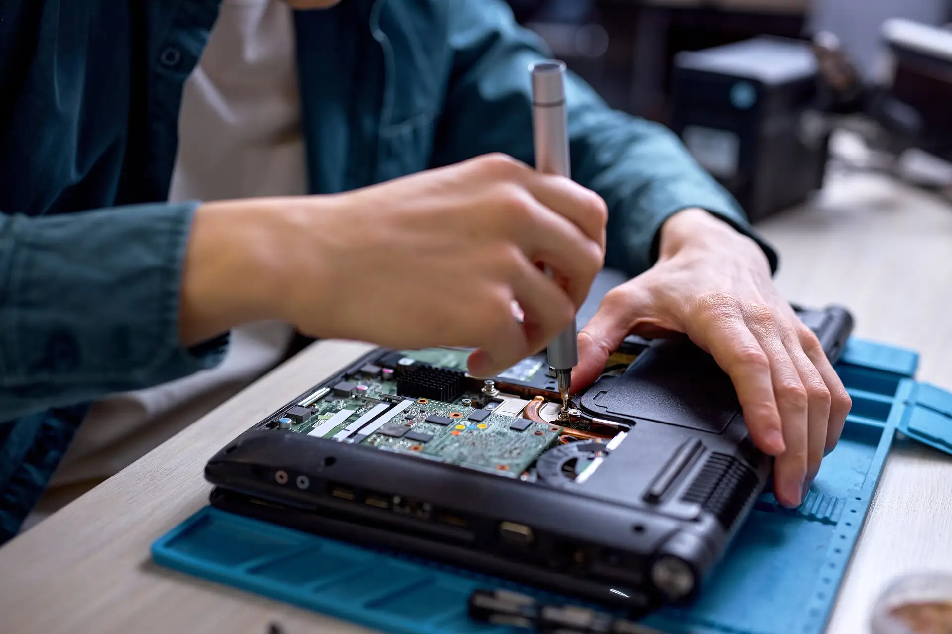 Techniker löst mit einem Schraubendreher Schrauben an einem elektronischen Gerät